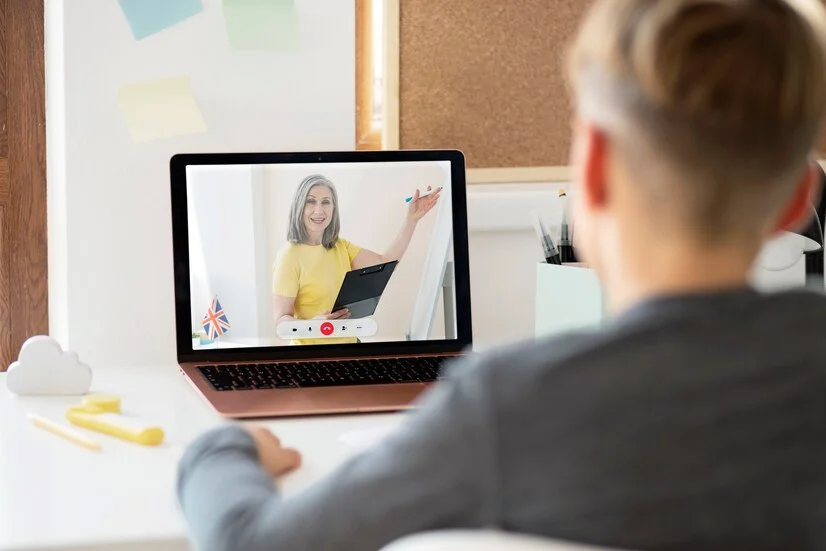 A teacher conducting an online class, using interactive tools on a laptop while students participate from their own devices, emphasizing the dynamic nature of online learning