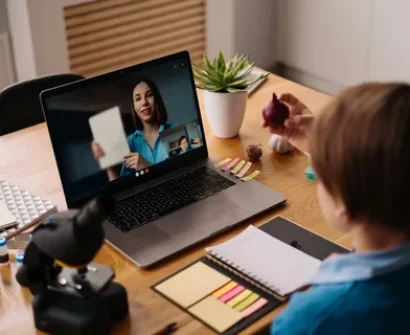 A teacher in Pakistan transitioning from traditional classroom teaching to online teaching, using a laptop and video conferencing tools to connect with students remotely.